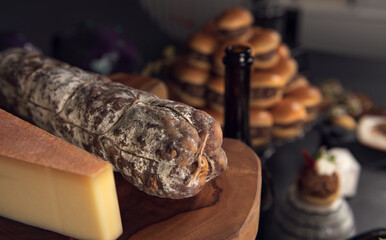 Rustic cured sausage and cheese on wooden board with blurred background