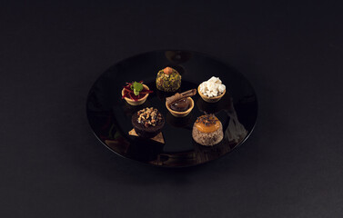 Assorted gourmet mini desserts on black plate