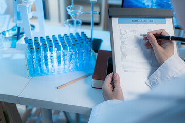 A close-up view of a scientist reviewing hematology lab data on a clipboard in a modern laboratory...