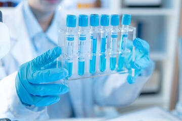A chemistry researcher in a laboratory surrounded by scientific equipment and test tubes,...