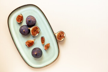 Purple ripe figs and slices on plate top view on a stone background
