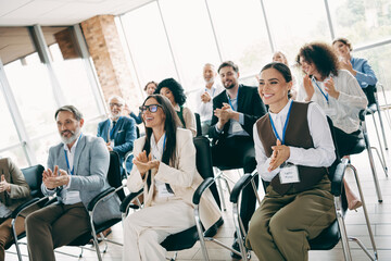 Naklejka premium Team of professionals attending a corporate seminar in a bright office setting, applauding and participating with enthusiastic engagement