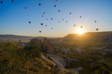 Cappadocia, Turkey - May 5 2025: Many colorful hot air balloons fly in the sky over a mountain valley at summer sunrise in Goreme