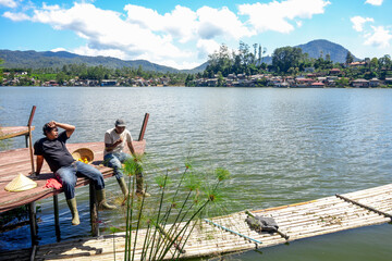 Relaxing Lakeside Moment Two Friends Share in Thai Village on Sunny Summer Day