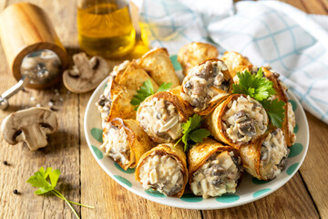 Crispy lavash rolls with mushroom filling, cheese and herbs on a rustic wooden table.