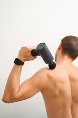 Fototapeta premium Man using massage gun for upper back therapy