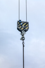 Obraz premium Industrial crane hook with metal chain hanging against cloudy sky background