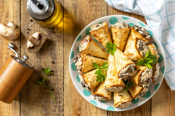 Crispy lavash rolls with mushroom filling, cheese and herbs on a rustic wooden table. Top view.