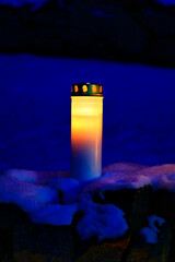 Solitary grave candle burning at the blue hour of the morning before sunrise on Christmas Day.  Vertical view. 