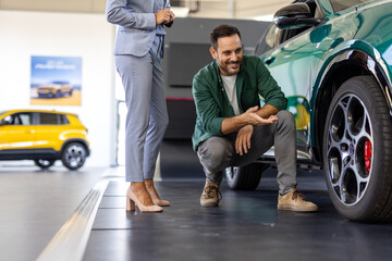 Man checking out wheels and tires of a new car at the dealership. Professional saleswoman car dealer helping her customer buying choosing automobile luxury driving © Graphicroyalty