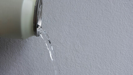 Hand pouring beverage from metal can on white background.	