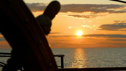 sunset at sea through an old ship's wheel