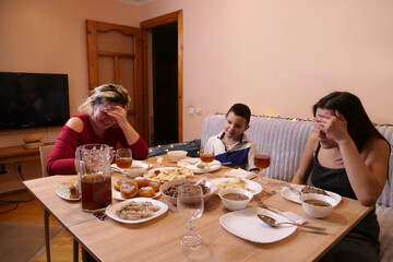A family celebrates Christmas or New Year together, a woman with children having dinner near the Christmas tree.