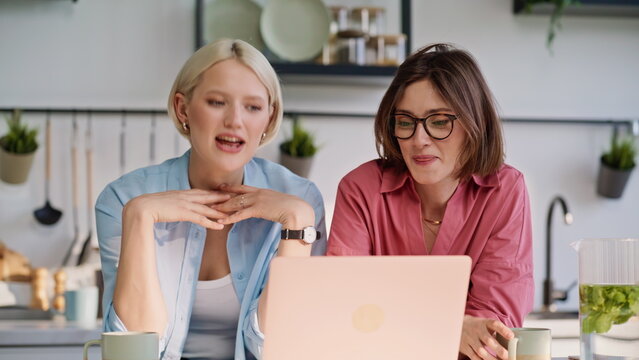 Lesbian pair talking virtual call using computer in kitchen together closeup - Powered by Adobe