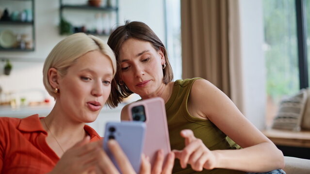Excited women looking smartphones in living room closeup. Besties having fun