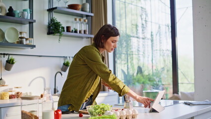 Brunette housewife drinking coffee turning tab at bright kitchen window closeup