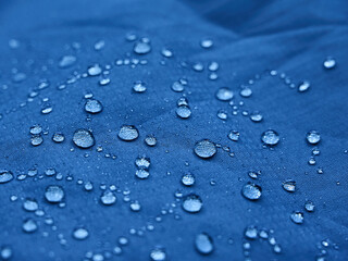 Water drops on waterproof membrane fabric. Detail view of texture of blue waterproof cloth.