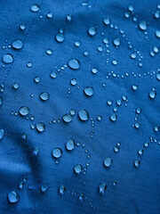 Water drops on waterproof membrane fabric. Detail view of texture of blue waterproof cloth.