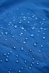 Water drops on waterproof membrane fabric. Detail view of texture of blue waterproof cloth.