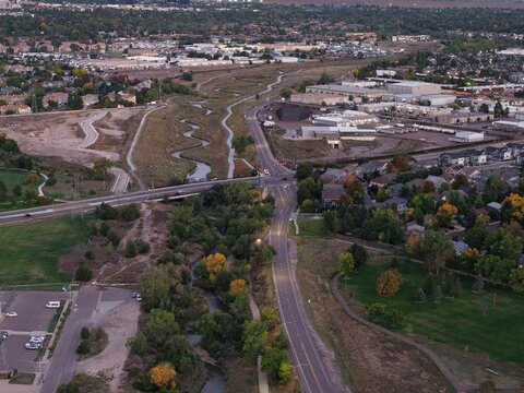 Drone capture of sunset view of Colorado town blending homes, industry, parks, and nature in vibrant community harmony
