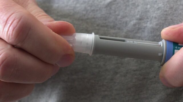 Closeup macro: Needle tip is screwed into medication injection pen