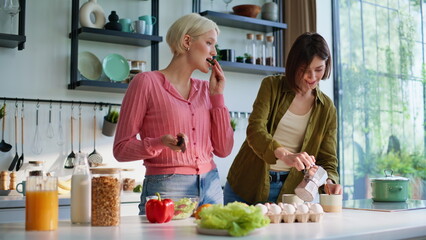 Cooking sisters standing kitchen closeup. Happy rejoicing girls preparing salad
