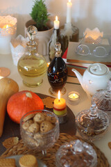 Lit candles, cookies, chocolate, nuts, tea, wine, pumpkins, books, reading glasses and autumn leaves on the table. Autumnal hygge at home. Selective focus.
