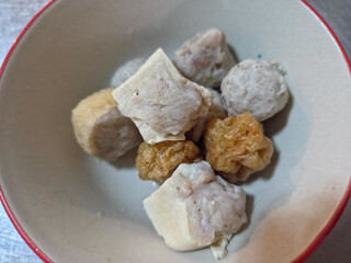 A bowl of various fish balls and fish cakes. This type of dish is commonly found in Southeast Asian cuisine, particularly in noodle soups. 