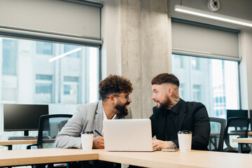 Diverse business professionals collaborating on laptop in modern office