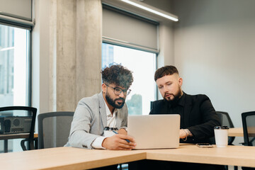 Obraz premium Businessmen collaborating on a laptop during office meeting