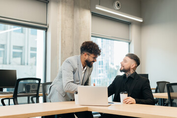 Business partners smiling talking shaking hands in office