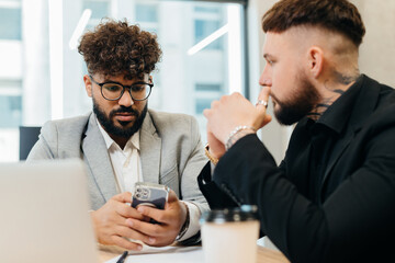 Business professionals collaborating and viewing smartphone in office