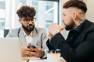 Two diverse business men discussing information on smartphone
