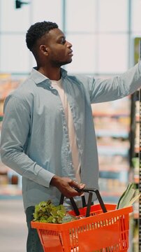 African American man with basket chooses product in store