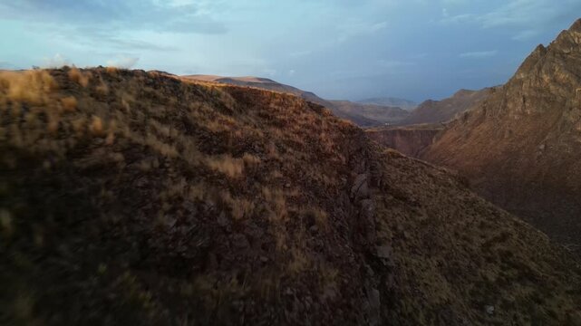 4K drone footage of a tranquil Andean valley at dusk, the landscape glowing faintly gold as cool blue shadows settle across the mountains.