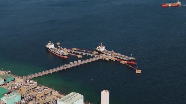 Aerial view of petrochemical tankers docked at Labuan port, Malaysia, showing industrial export terminal and methanol shipping operations over the deep blue sea.