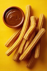 Crispy Churros with Chocolate Sauce on a Yellow Background.