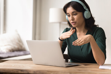 Young female in earphones speak using sign language via notebook © fizkes