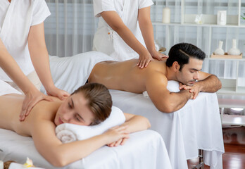 Fototapeta premium Caucasian couple customer enjoying relaxing anti-stress spa massage and pampering with beauty skin recreation leisure in day light ambient salon spa at luxury resort or hotel. Quiescent