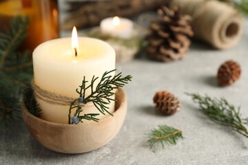 Burning candle with pinecone scent on light grey table, space for text