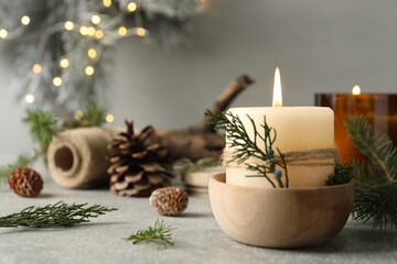 Burning candle with pinecone scent on light grey table, space for text
