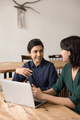 Millennial female employee explain project to business partner by notebook