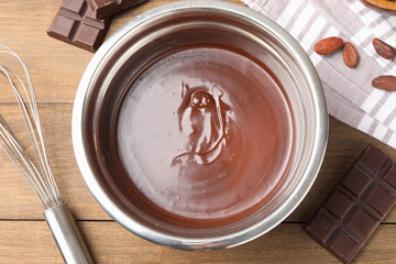 Melted chocolate, beans and pieces on wooden table, flat lay