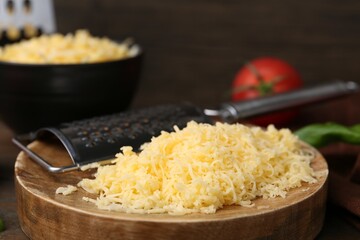 Grated cheese, grater, tomato and basil on table, closeup