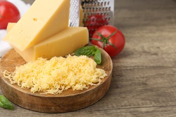 Grated cheese, grater and products on wooden table, closeup. Space for text