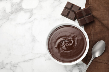 Melted chocolate in bowl, pieces and spoon on white marble table, flat lay. Space for text