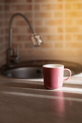 A glass or mug filled with fresh water stands near a kitchen faucet