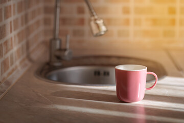 A glass or mug filled with fresh water stands near a kitchen faucet.