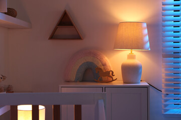 Lamp and toys on dresser in baby's room at night © New Africa