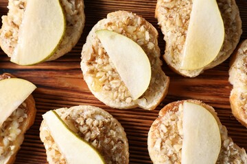 Tasty bruschettas with apples, honey and walnuts on wooden table, flat lay